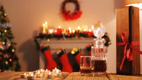 botella de whisky, vidrio y caja de regalos en una mesa de madera