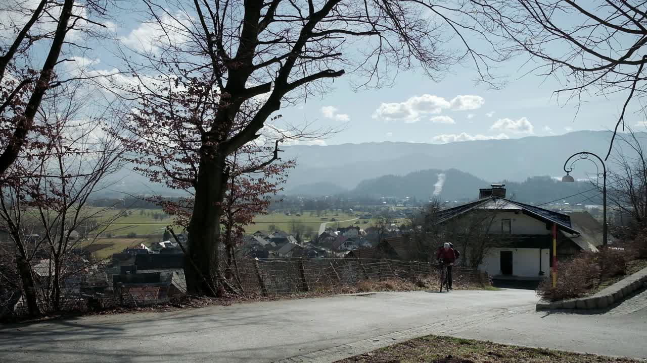 블레드 호수를 배경으로 자전거를 타고 오르막길을 오르기 위해 고군분투하는 남자
