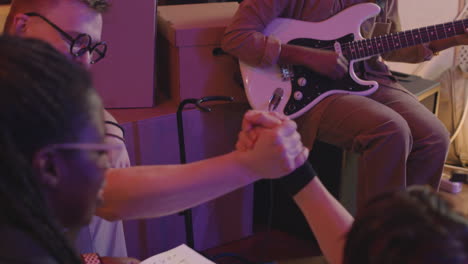 banda de música multiétnica discutiendo la canción juntos mientras ensayan en el estudio de grabación 1