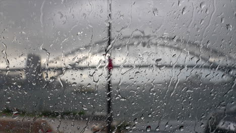 Gotas-De-Lluvia-Golpeando-El-Parabrisas-De-Un-Automóvil-Con-El-Puerto-De-Sydney-En-El-Fondo