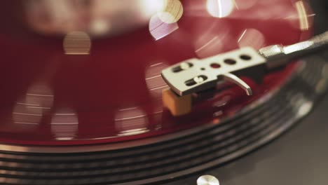 vinyl player on a sunset background with a bokeh lights of the evening city. the girl's hand places the needle on a rotating red vinyl plate. included gramophone and rotating plate