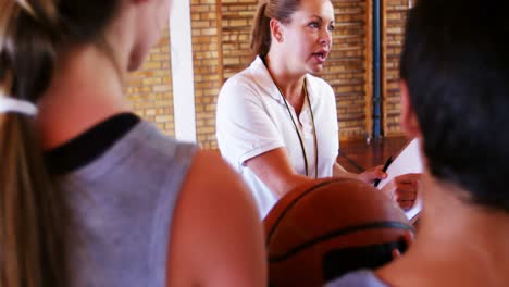 entrenadora instruyendo a los escolares en la cancha de baloncesto