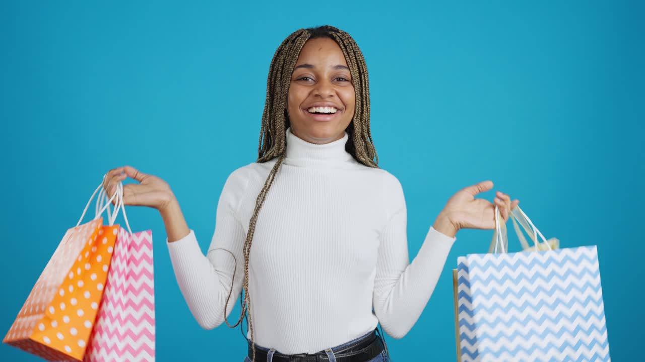 Happy Young Woman Showing Off Shopping Bags on Blue Background