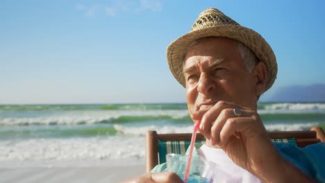 Vista-Frontal-De-Un-Hombre-Caucásico-Senior-Activo-Bebiendo-Un-Cóctel-En-La-Playa-4k