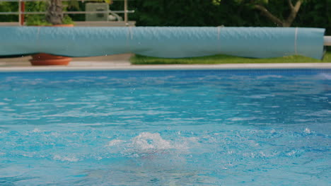 joven salpica agua en la piscina 1