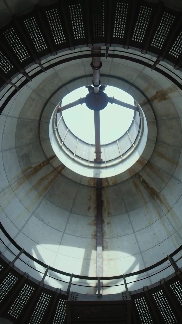 Vertical video: Tilting camera revealing centered skylight and catwalk inside silo for inspection