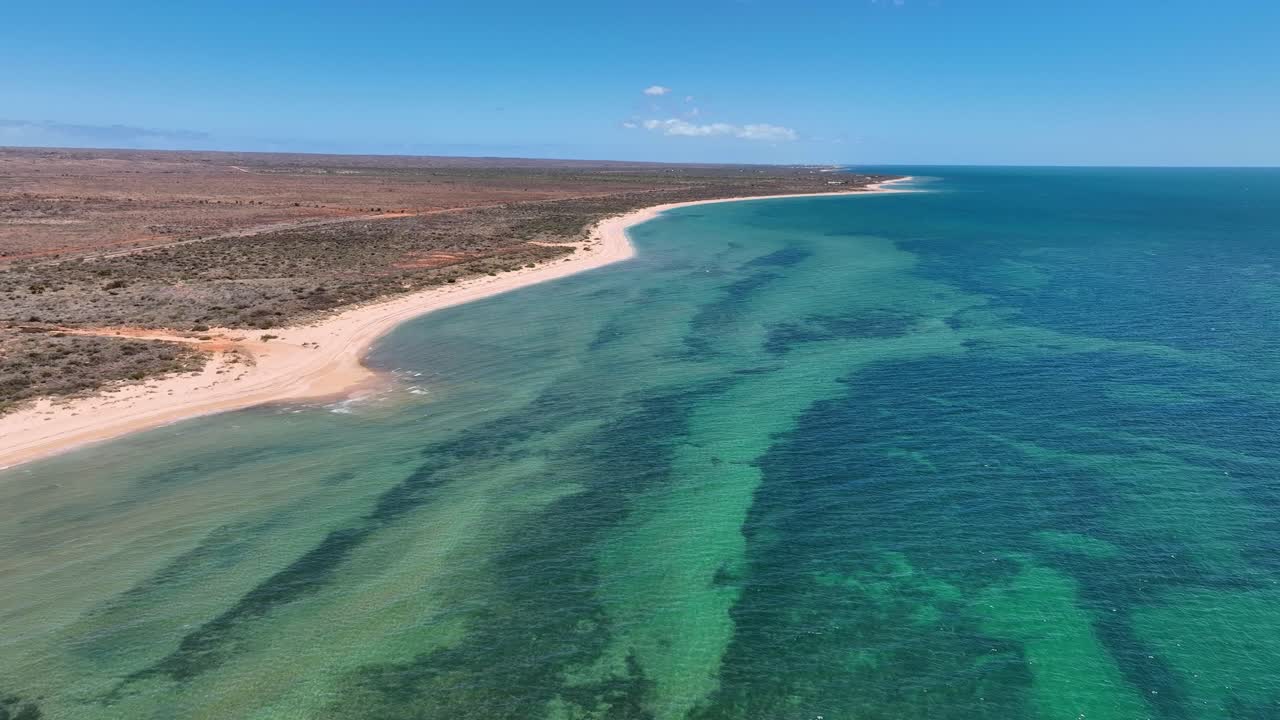 Aerial pan shot of a turquoise bay along the vacant beach in Exmounth, Australia during daytime.