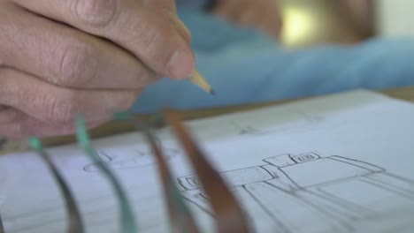 hand-drawing-with-pencil-and-paper-on-a-wooden-table