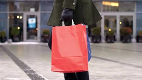 low section of man with shopping bags walking the street