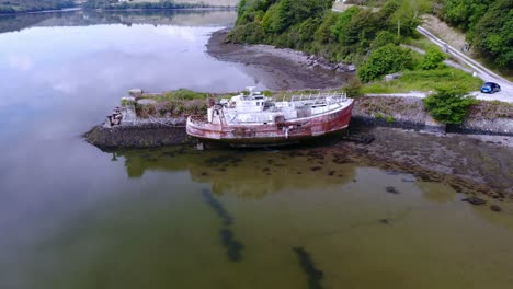 Abandoned-old-river-boat-and-a-pier,-drone-footage-circle-flying