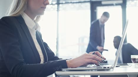 woman texting on laptop in coworking space