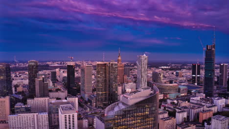 Fly-forwards-above-downtown-skyscrapers-in-sunset-time.-Hyperlapse-footage-of-city-centre.-Dimming-pink-sky-changing-colour-to-blue.-Warsaw,-Poland
