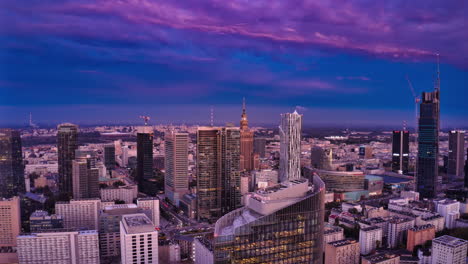 Fliegen-Sie-Bei-Sonnenuntergang-Vorwärts-über-Die-Wolkenkratzer-Der-Innenstadt.-Hyperlapse-Aufnahmen-Des-Stadtzentrums.-Dimmender-Rosa-Himmel,-Der-Seine-Farbe-Zu-Blau-ändert.-Warschau,-Polen