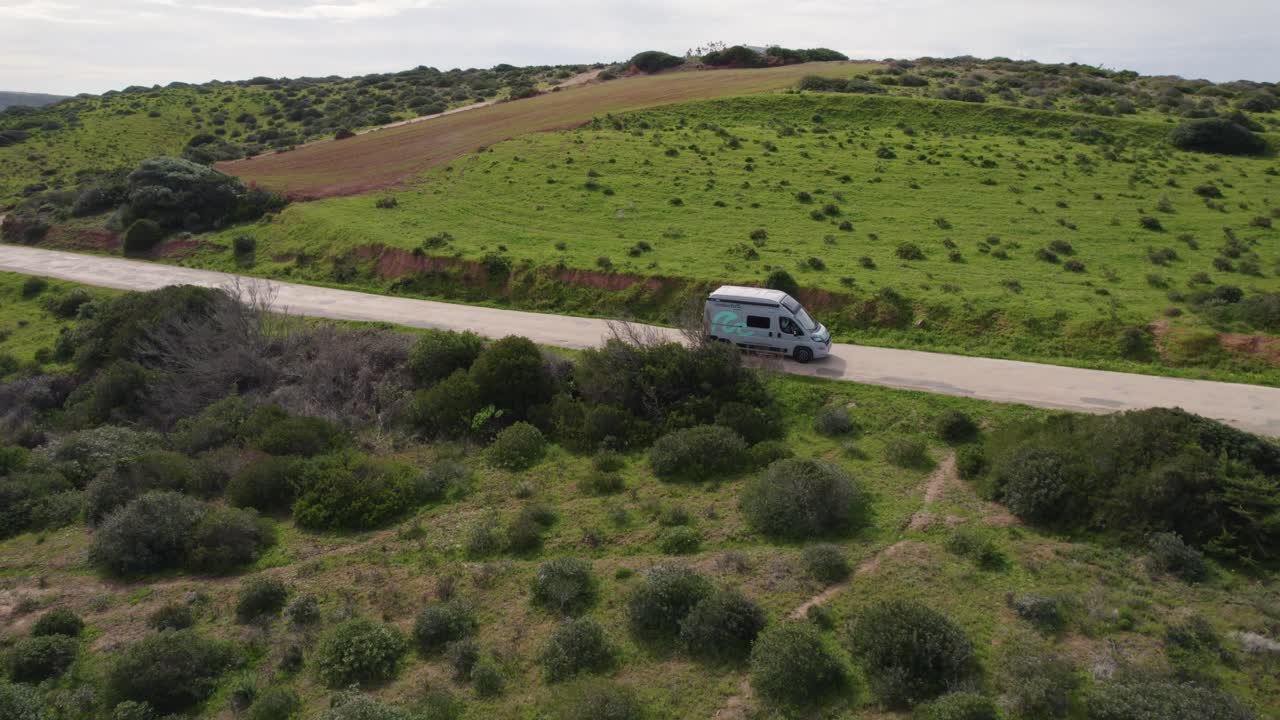 Drone flight flowing wan car on the road, passing near by other motor home, recorded at Bordeira Portugal hillside coastline