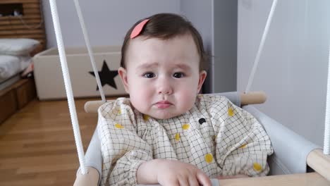 One-Year-Old-Baby-Girl-Crying-While-On-Swing-Chair-Inside-The-Bedroom