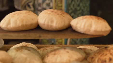 freshly baked bread being taken out of traditional oven on wooden paddle and served in bakery