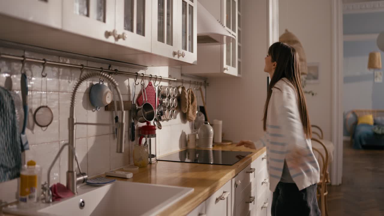 Donna che ripone i piatti in un pensile della cucina