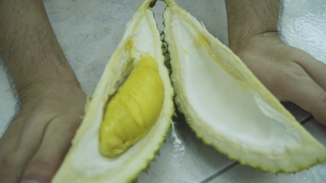Man Hands Opening Half Of The Mao Shan Wang Durian - close up