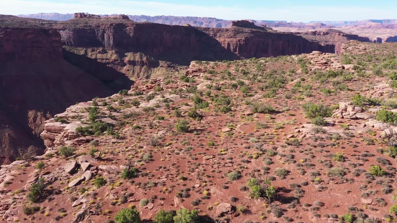 Vista aerea di un altopiano, poi sorvolando la scogliera che rivela il fiume Colorado e il canyon sottostante, vicino a Moab, Utah.