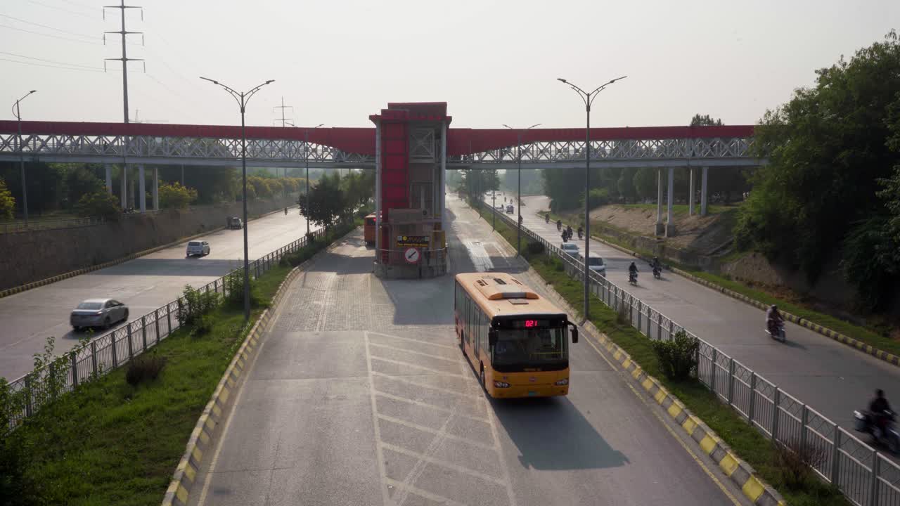 Bird's Eye View of City Metro Bus Station with Highway, Pedestrian Bridge, and Bustling City Life.