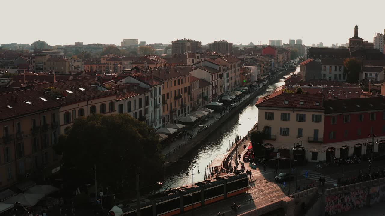 Scena del canale dei Navigli di Milano con un treno pendolare che attraversa il paesaggio urbano italiano