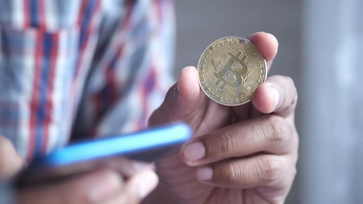 Persona che tiene una moneta Bitcoin
