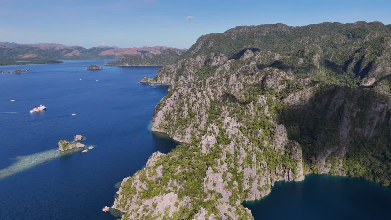 Aerial drone view of Coron Island’s dramatic cliffs, tropical greenery, and idyllic turquoise waters, Philippines. Wide rotating shot.