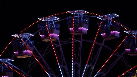 wheel with cabins rotating on black background, people enjoying holidays on playground