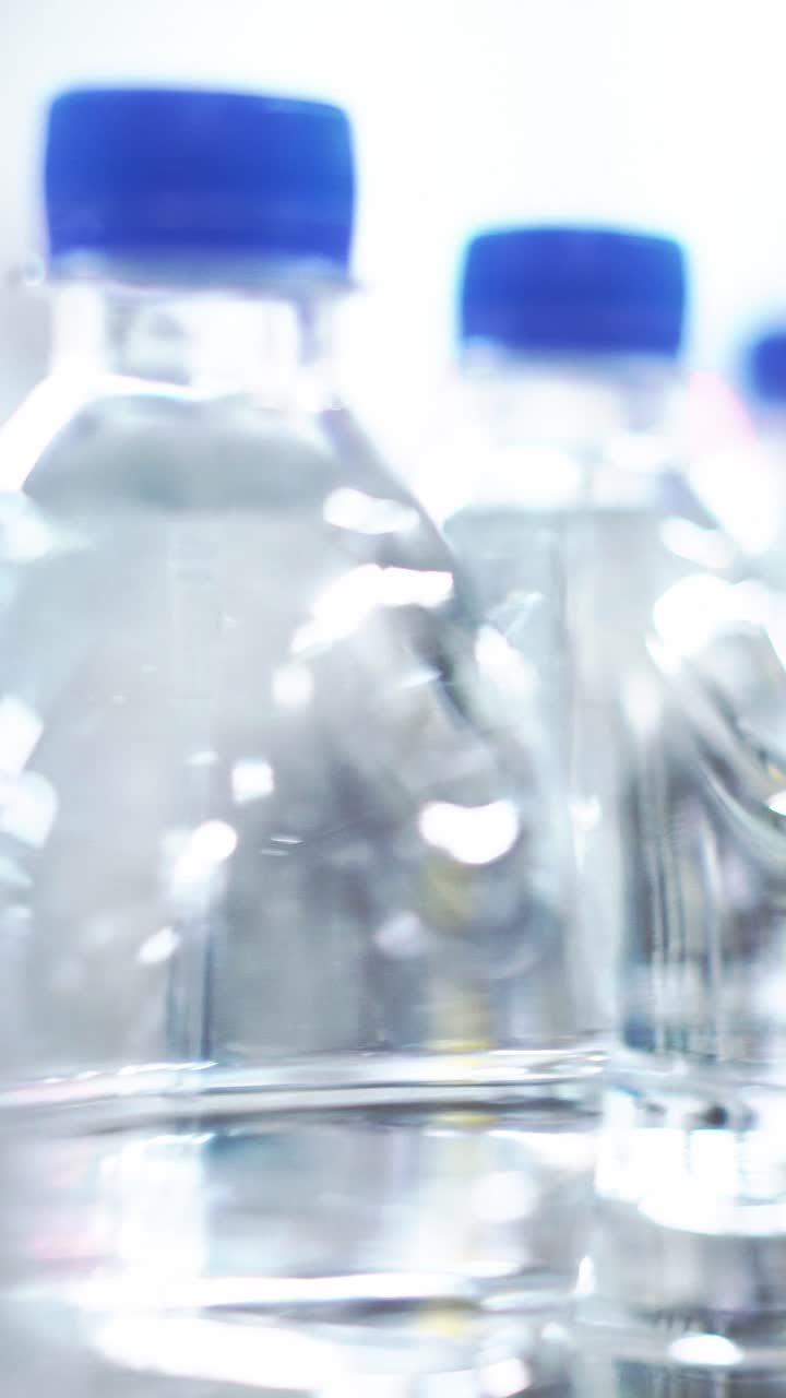 Clear plastic water bottles with blue caps arranged in a blurred background for product display