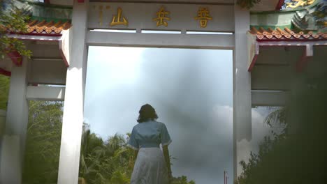 woman in blue and white dress walk to chinese temple to the arch