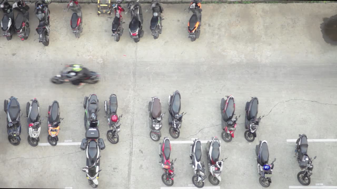 Top view of an outdoor motorbike parking lot. People passing by in the middle of the frame