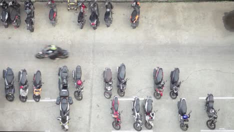 top view of an outdoor motorbike parking lot. people passing by in the middle of the frame