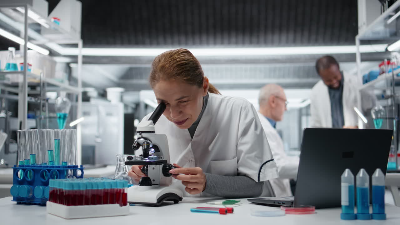 Portrait of smiling scientist examining pathology slides under microscope