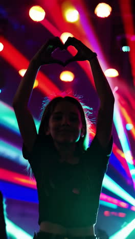 girl making a heart shape at a concert