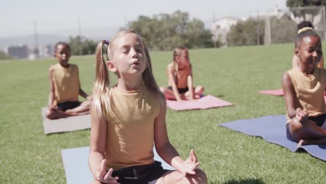 focused diverse schoolgirls practicing yoga and meditating at stadium in slow motion