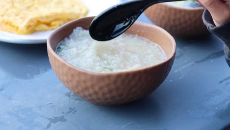 adding toppings to rice porridge, served with omelet