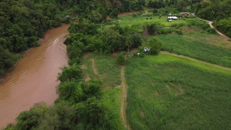 Toma-Aérea-De-Seguimiento-De-Un-Barco-Que-Viaja-A-Lo-Largo-Del-Río-Pai-En-Tailandia.