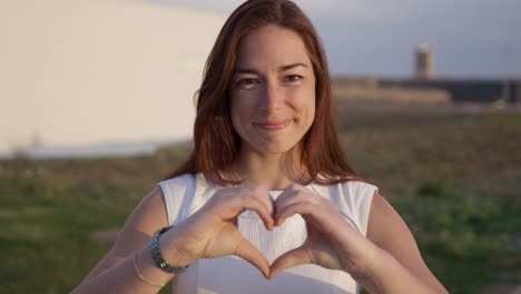 attractive young lady making heart shape with hands.