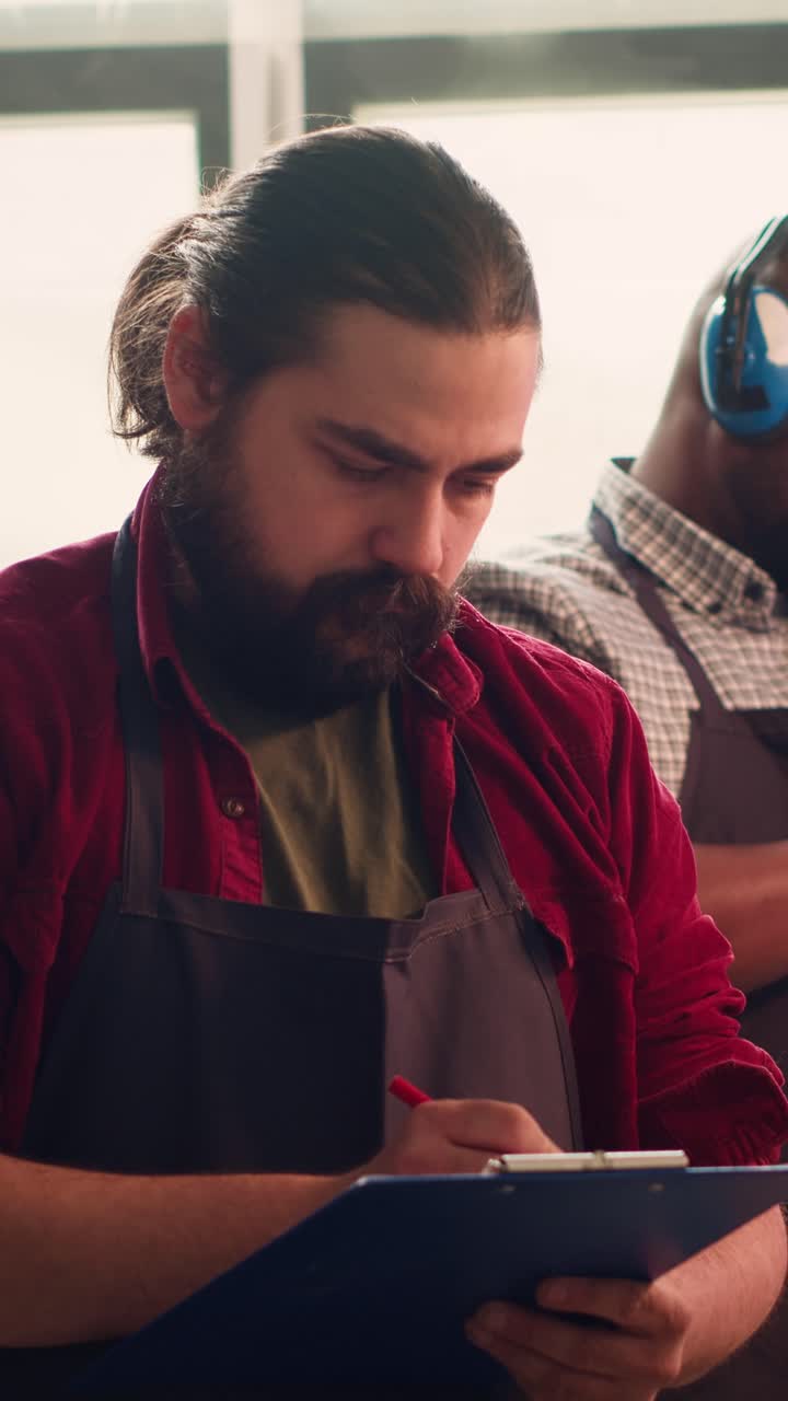 Focused Craftsman Writing Notes on a Clipboard in a Workshop