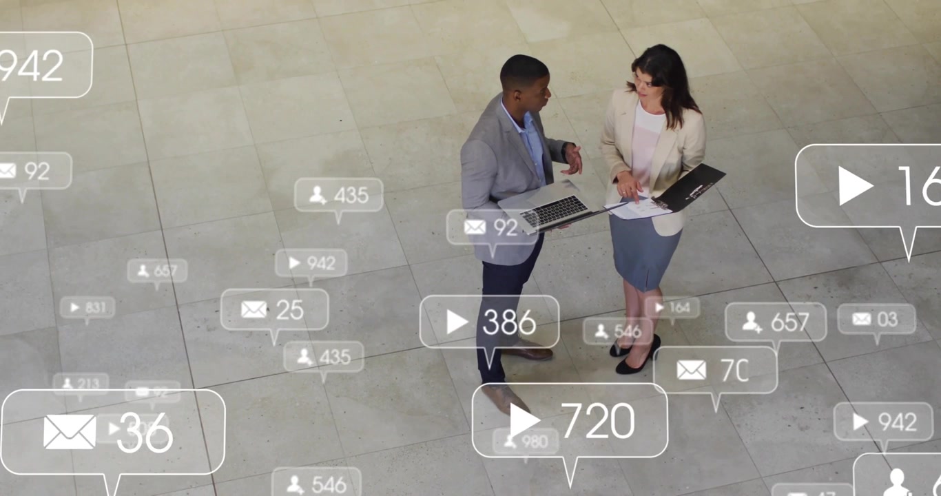 Duo di marketing che gesticola e prende appunti mentre esamina le metriche di coinvolgimento, attivando icone fluttuanti