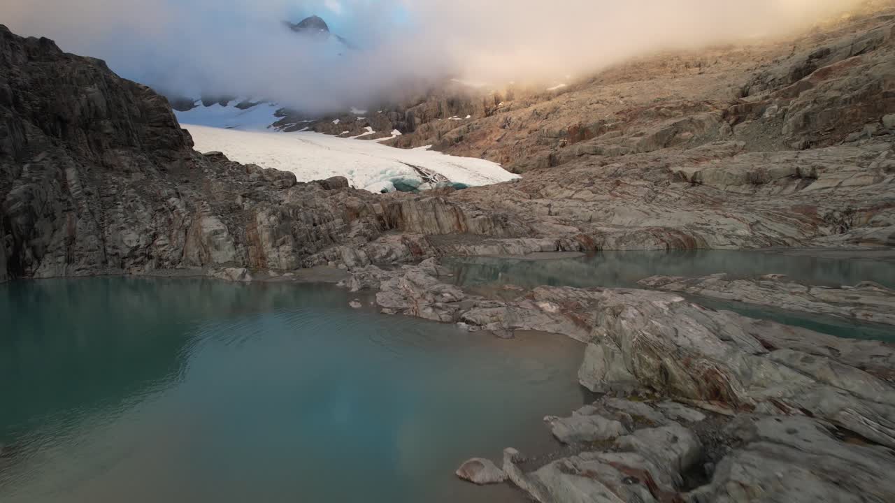 Ripresa aerea sopra un lago verso spettacolari formazioni di ghiaccio del Ghiacciaio Brewster, Parco Nazionale Aspiring, Nuova Zelanda