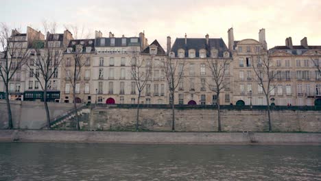 parisian architecture with cream colors, trees without leaves for the winter season, seine river, paris, france