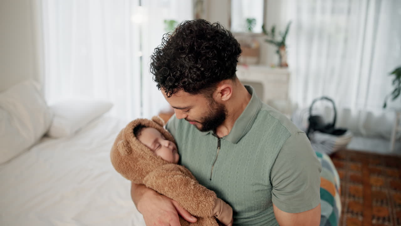 Un padre che culla un bambino che dorme in una tutina da orsetto