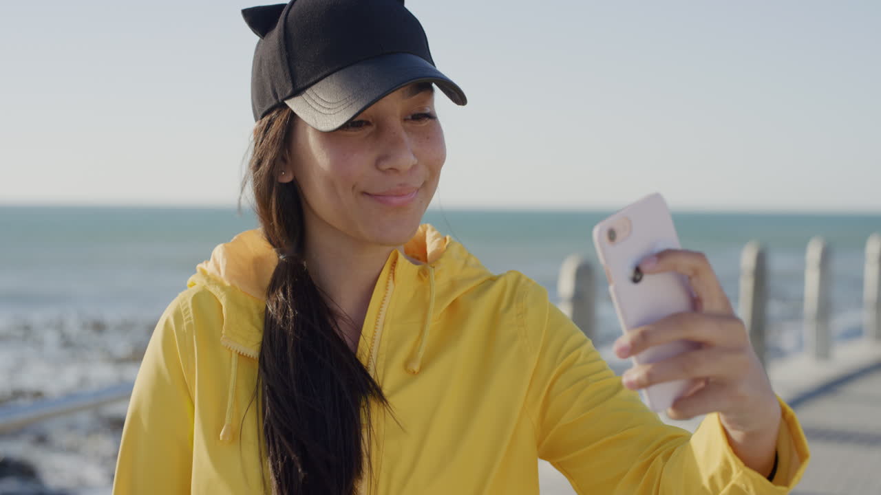 retrato de una adolescente bonita usando un teléfono inteligente posando tomando una foto selfie en una hermosa playa soleada disfrutando de una comunicación móvil relajada