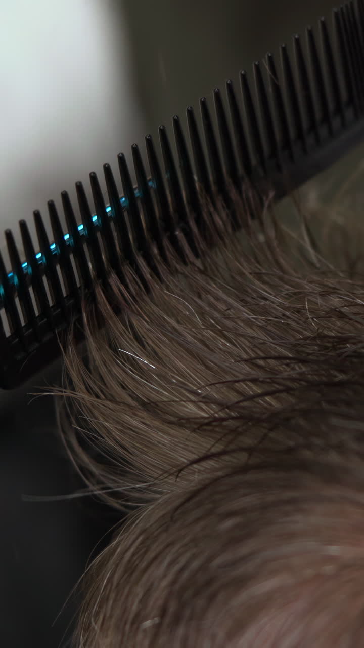 Close-up of Brown Hair Being Combed with a Black Comb