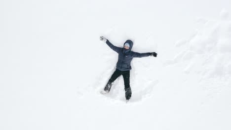 AERIAL---Person-making-a-snow-angel-in-Kolasin-ski-resort,-Montenegro,-rising-shot