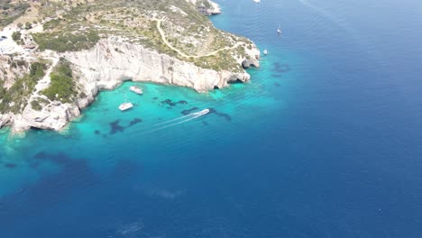 Barco-Navegando-En-La-Bahía-Paraíso-Llamada-Laguna-Azul-Con-Cuevas-Y-Mar-Turquesa-Claro-En-La-Isla-De-Zakynthos,-Grecia