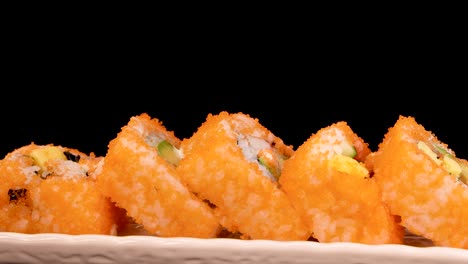 california roll sushi pieces rotate smoothly on a white plate, illuminated by soft studio lighting against a seamless black background, highlighting texture and color