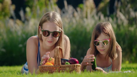 two friends on a picnic, near them a basket of fresh vegetables