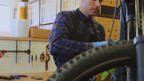 Man-repairing-bicycle-in-workshop-4k